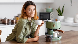 Mujer joven tomando un café recién hecho en la cocina de su casa